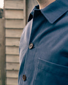 Close-up of a person wearing a Cook & Butler work jacket with a buttoned collar and chest pocket.