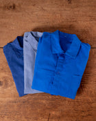 Folded blue work jackets on a wooden surface