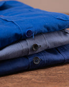 Stack of folded blue and grey jackets on a wooden surface