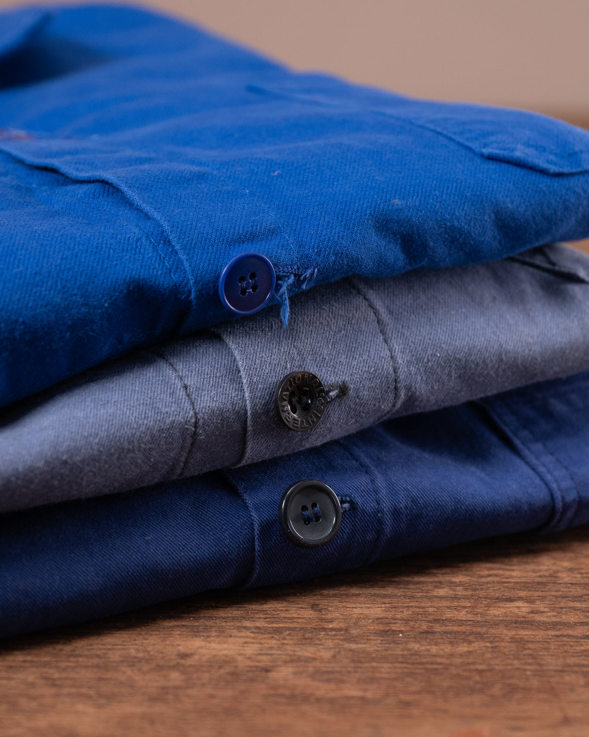 Stack of folded blue and grey jackets on a wooden surface